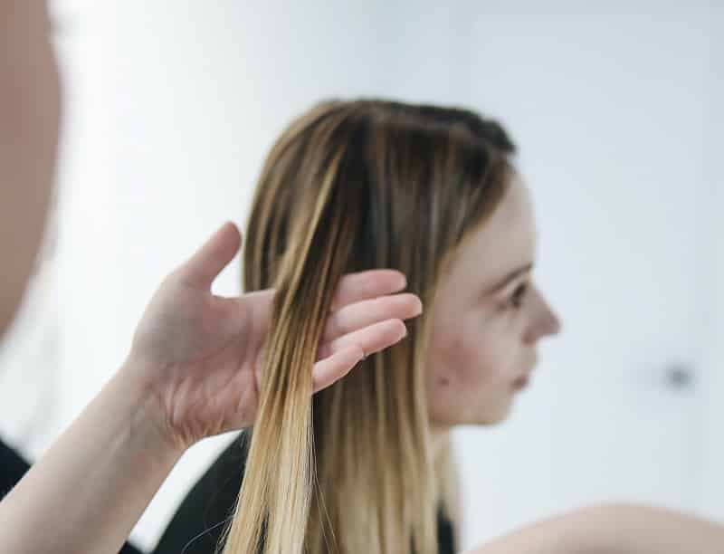 Person holding a woman's blonde straight hair